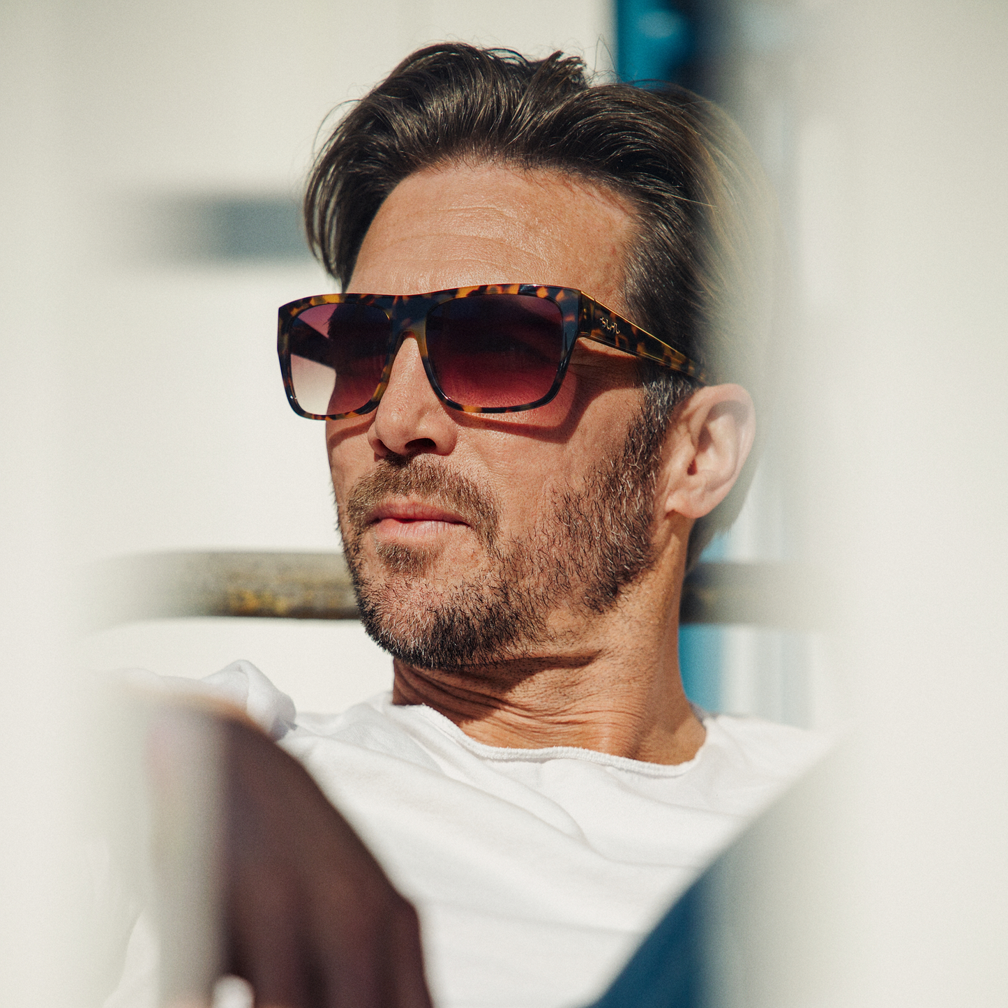 Man wearing tort / gradient brown sunglasses with a blurred background