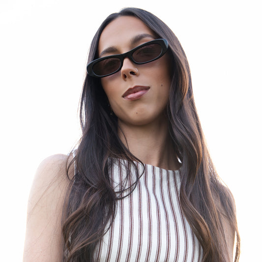 Woman wearing LULU black sunglasses with a white background