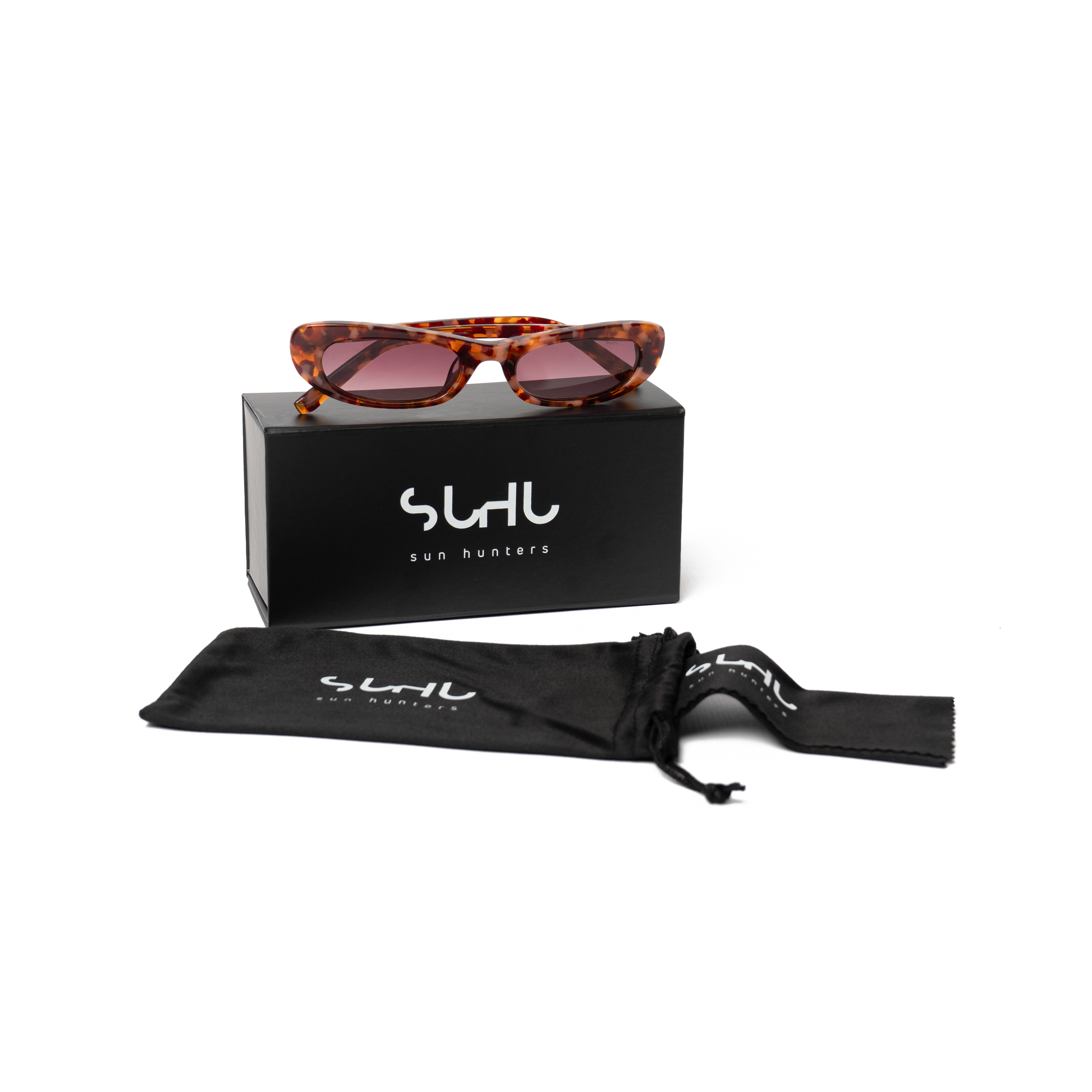 Sunglasses with rose-red frame gradient lenses on a black box with 'SUHU' branding, accompanied by a black drawstring bag.