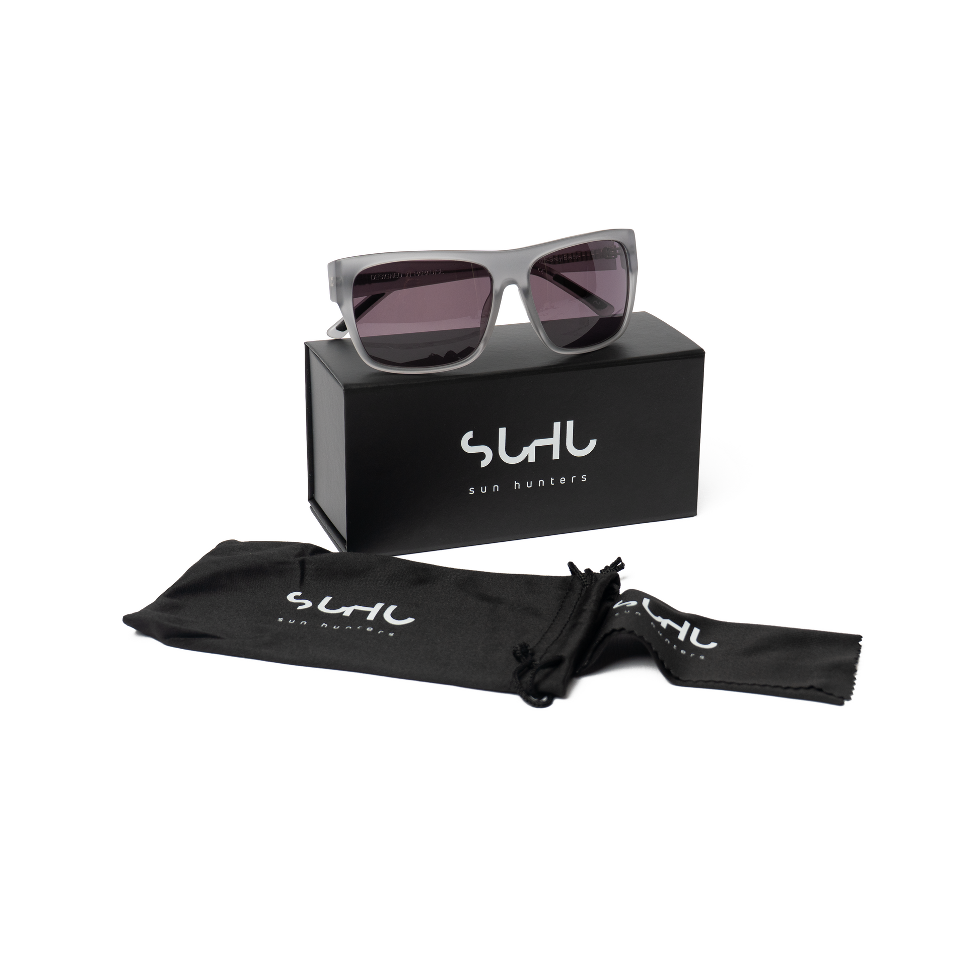 The DUDE sunglasses with matte grey acetate frames, a black case and box on a white background, featuring the brand 'Suhu'.